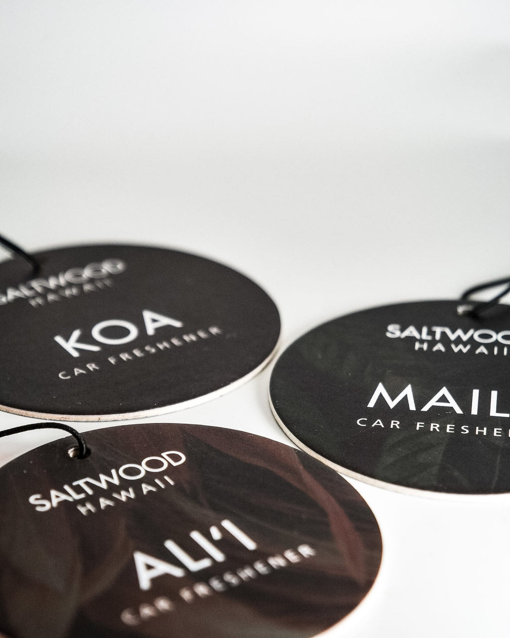 Three car freshener tags with brand names on a white background