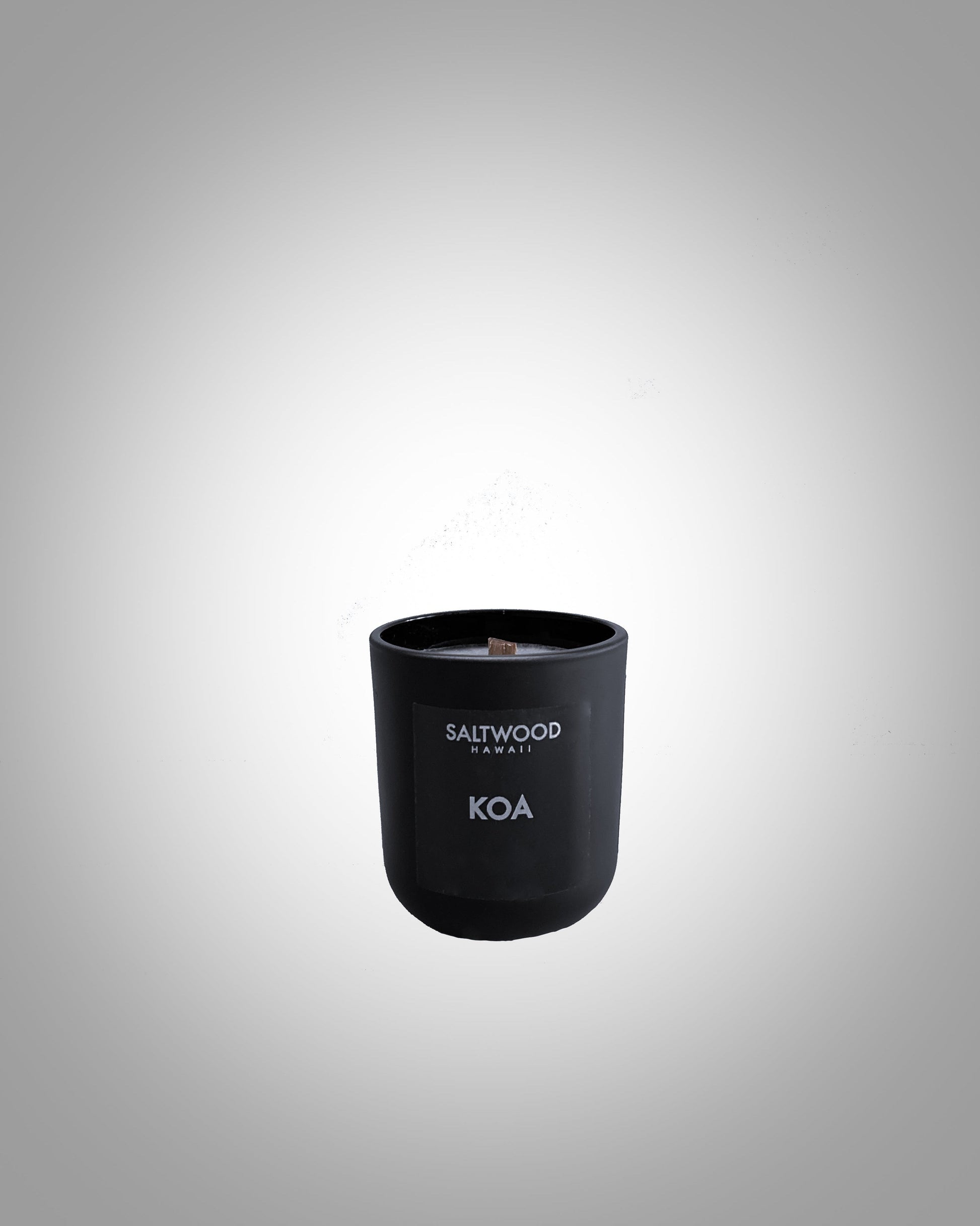 A 3 oz black candle with label that reads "Saltwood Hawaii Koa"